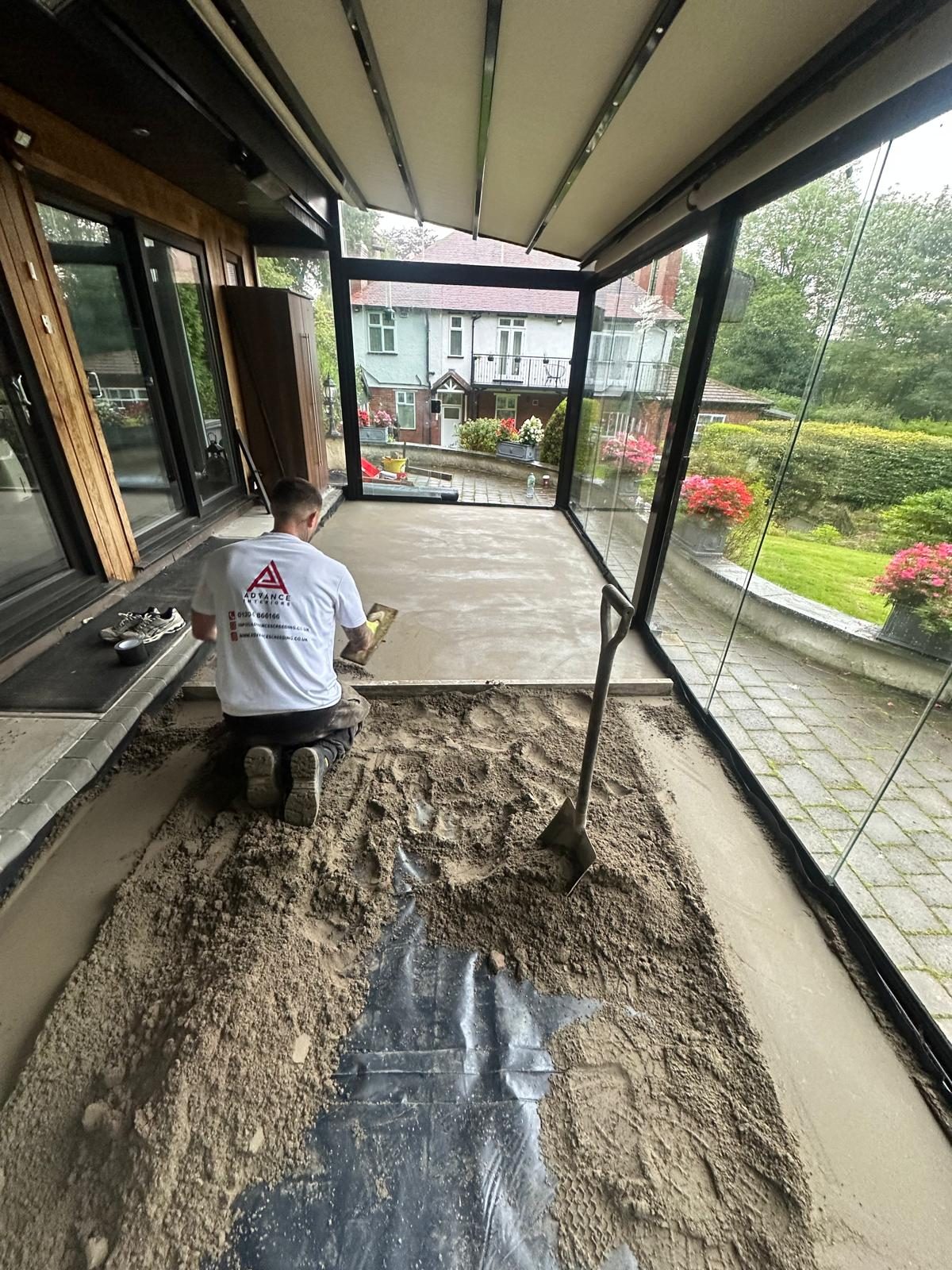Advance Interiors screeder kneeling on the boards, hand trowelling the Retanol screed in the summer room