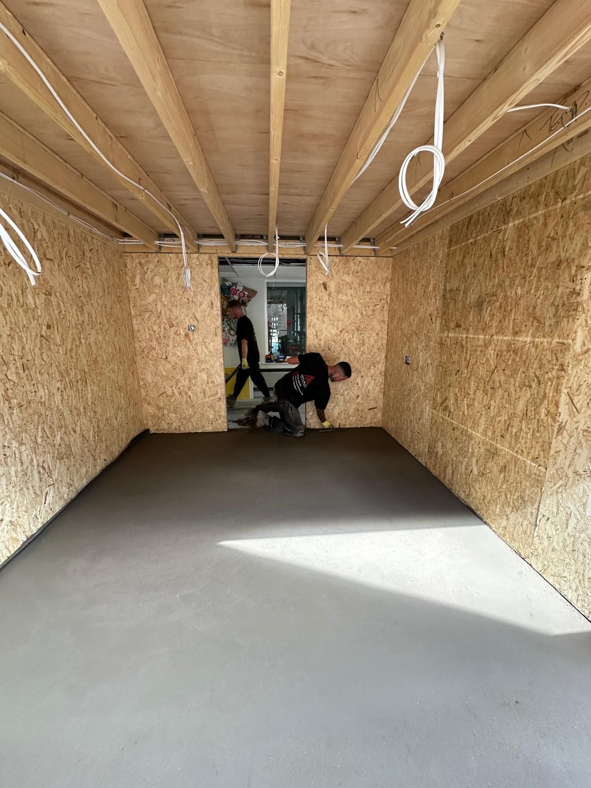 Screed being hand trowelled to a flat finish inside the extension