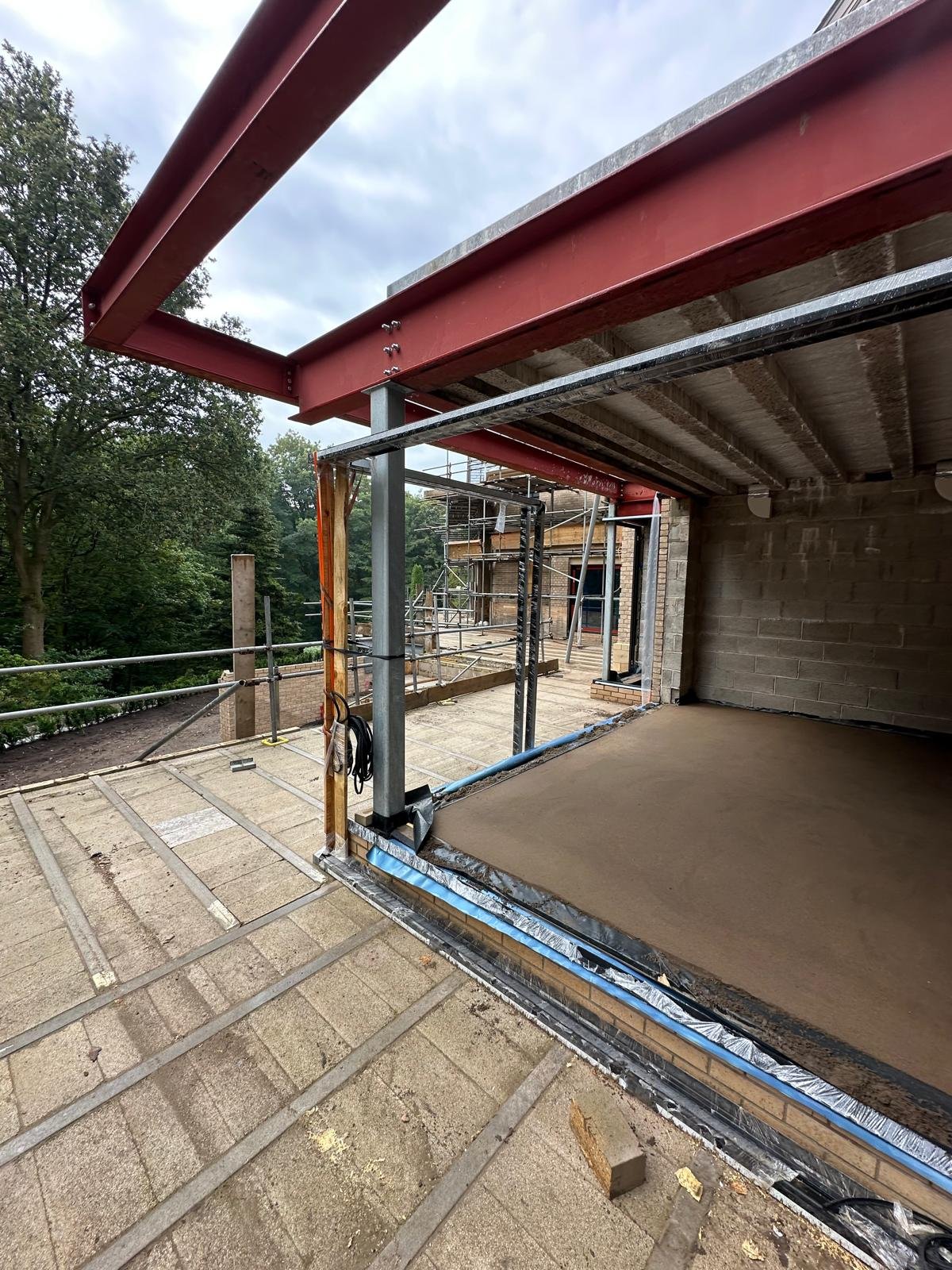 Screeded floor beneath the steel frame, with the balcony deck waiting for its screed