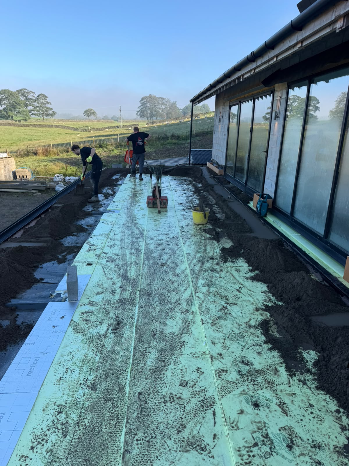 Advance Interiors screeders laying Retanol screed along the balcony beside the glazing at Pott Shrigley