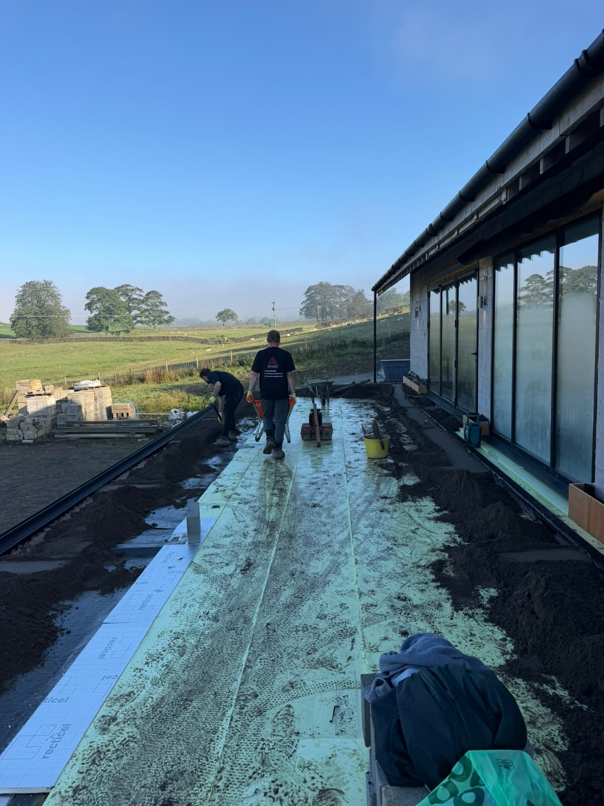 Screed being spread and levelled along the balcony at Pott Shrigley on a clear morning
